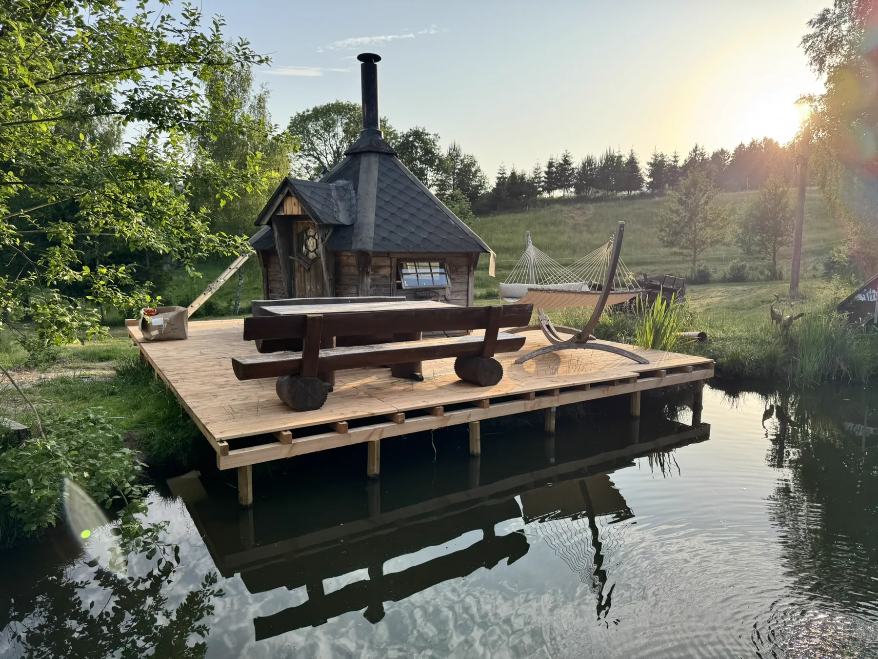 Grillkota der Dark Creek Ranch am Teich im Abendlicht
